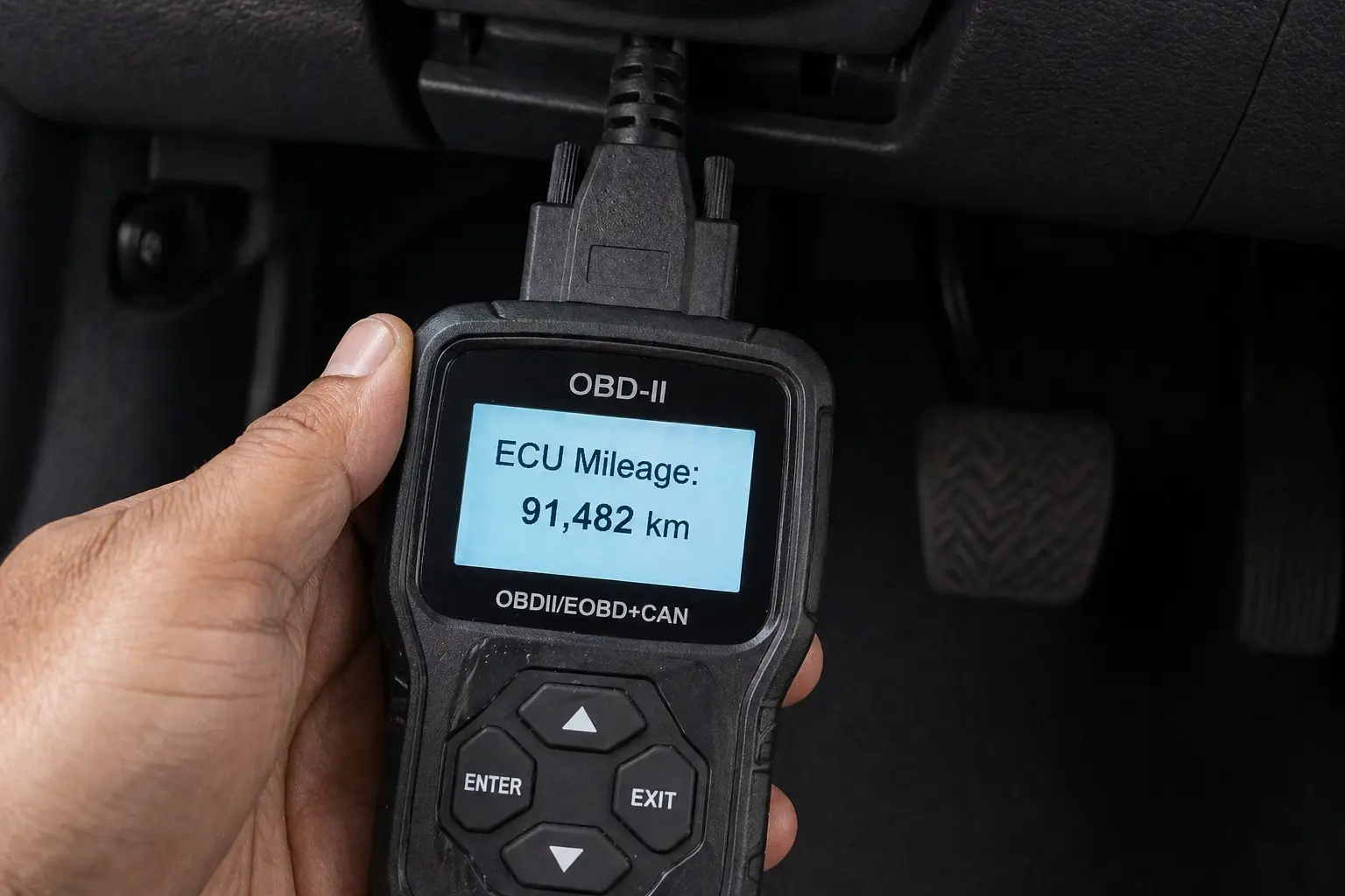 OBD-II reader displaying ECU mileage of 91,482 km plugged into a used car's diagnostic port — method to detect odometer rollback